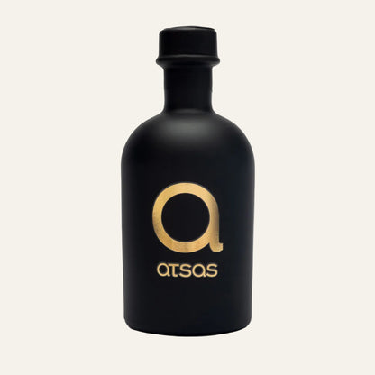 Black bottle of ATSAS Gold Blend olive oil with gold logo and text on a white background