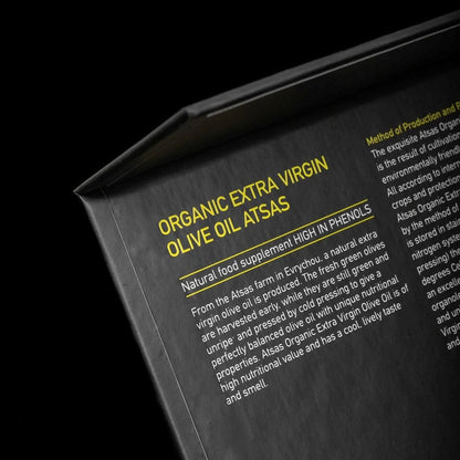 Close-up of a label for Atsas organic extra virgin olive oil with text on a black background.