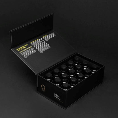 Black box containing multiple small dark bottles of olive oil on a black background